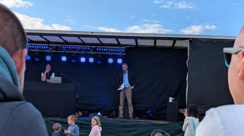 Der Bürgermeister spricht auf der Bühne des Gemeindefestes vor Zuhörern.