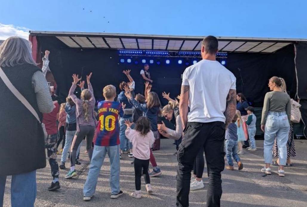 Kinder springen hoch und greifen nach Bonbons, die von einer Bühne geworfen werden.